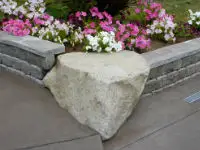 Massive boulder cornerstone connecting garden walls.