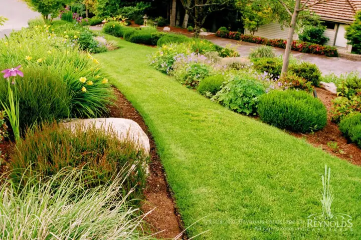Street-side lawn strip with manicured turf flanked by ornamental grasses and perennial garden borders
