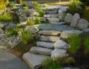 Natural boulder staircase with large flat stone steps ascending landscaped hillside with ornamental grasses and drought-tolerant plantings