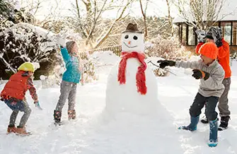 kids playing around a snowman